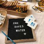 Board with letters that say One Saves Water along with water education giveaways