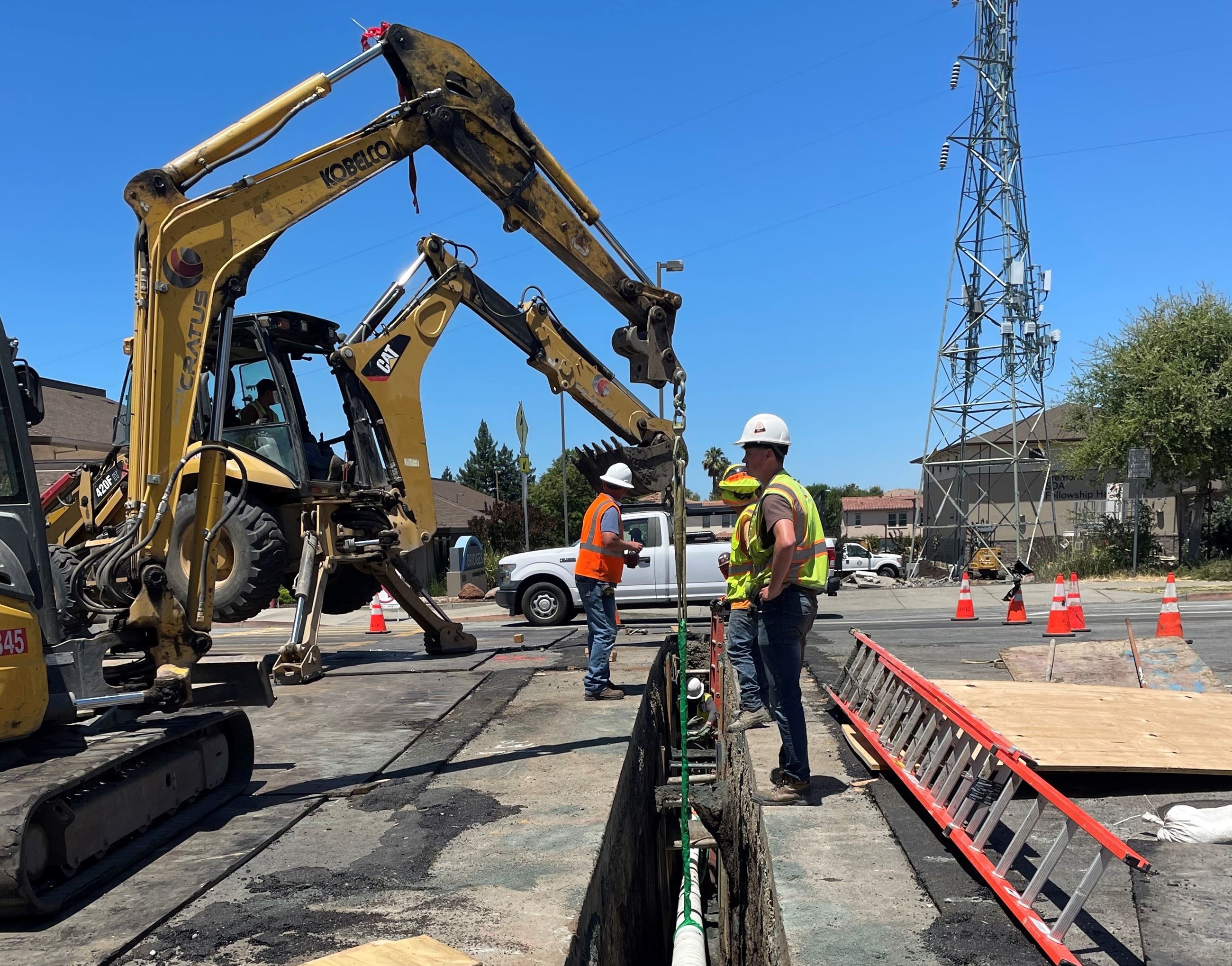 Construction workers using heavy machinery to repair an underground water main.